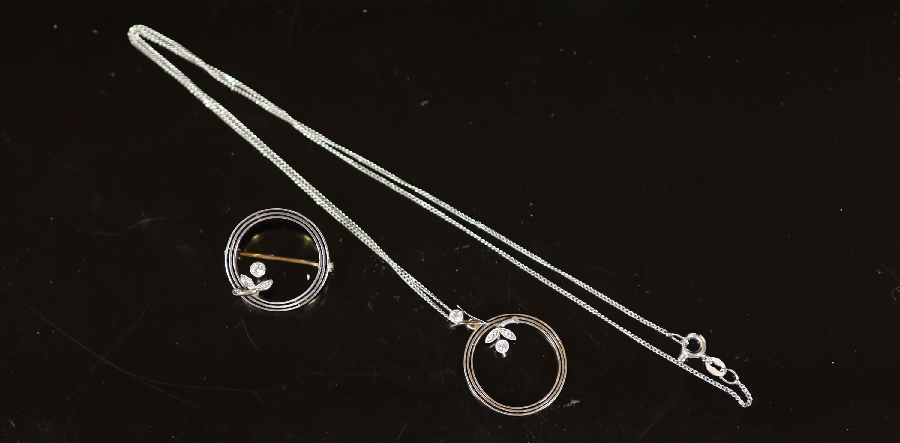 An early 20th century 15ct open work circular brooch with diamond set small flower and a matching pendant